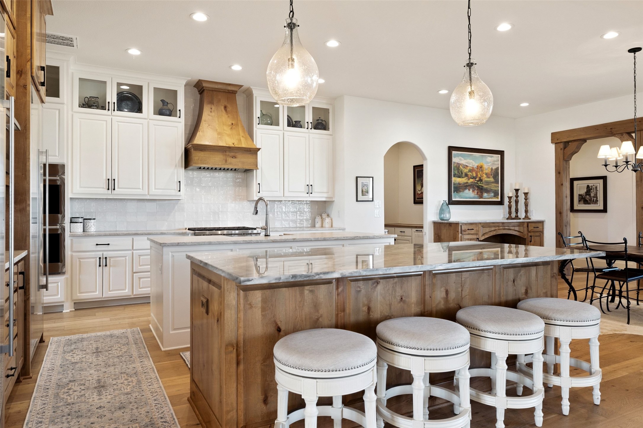 105 Deer Valley Road Georgetown, TX 78628 - Photo 9 of 40 Kitchen featuring light stone counters, decorative backsplash, light wood-style floors, two tone color scheme, and a breakfast bar