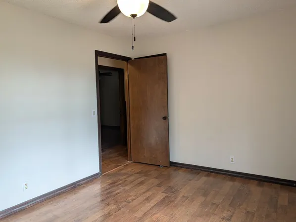 an empty room with closet and a ceiling fan
