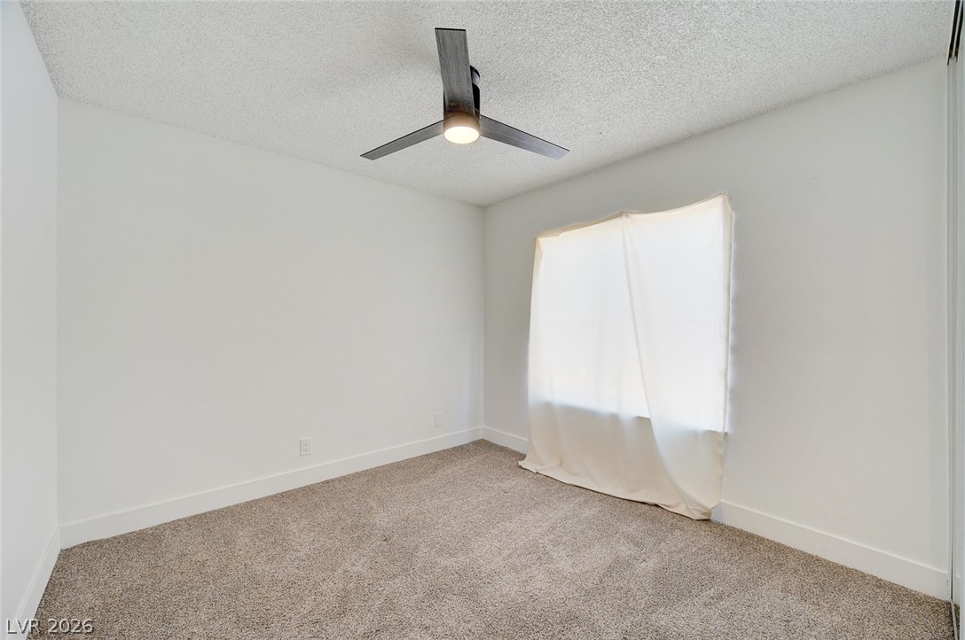 4840 Summerhill Road Las Vegas, NV 89121 - Photo 34 of 56 A well-lit bedroom three with fresh carpeting and a modern ceiling fan, offering a clean canvas for personalization.
