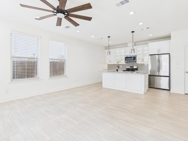 511 Richardson Street Athens, TX 75751 - Photo 39 of 40 Kitchen with open floor plan, appliances with stainless steel finishes, decorative light fixtures, a center island with sink, and white cabinetry