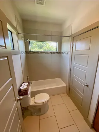 a bathroom with a granite countertop bathtub shower sink vanity and toilet
