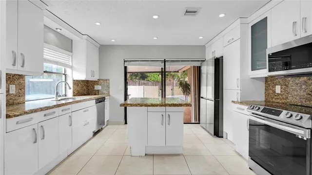 a kitchen with granite countertop white cabinets and white appliances