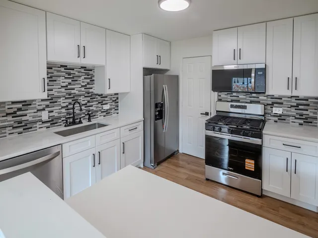 a kitchen with white cabinets and appliances