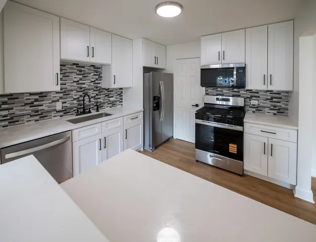 a kitchen with white cabinets and stainless steel appliances
