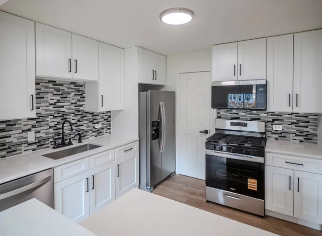 a kitchen with white cabinets and stainless steel appliances