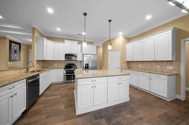 a kitchen with granite countertop a sink stainless steel appliances and cabinets