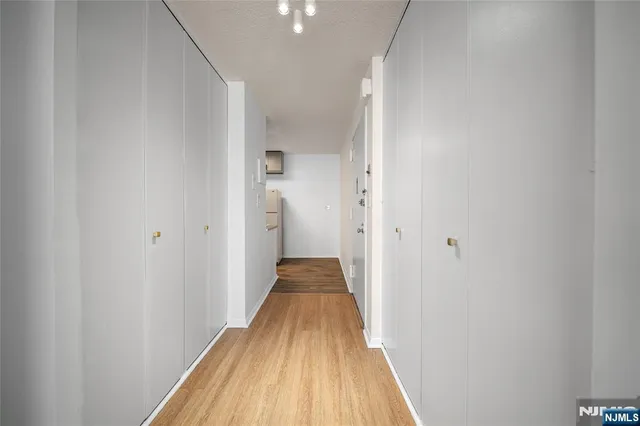 a view of a hallway with wooden floor and a bathroom