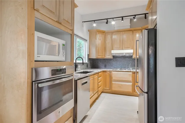 a kitchen with stainless steel appliances granite countertop a refrigerator and a sink