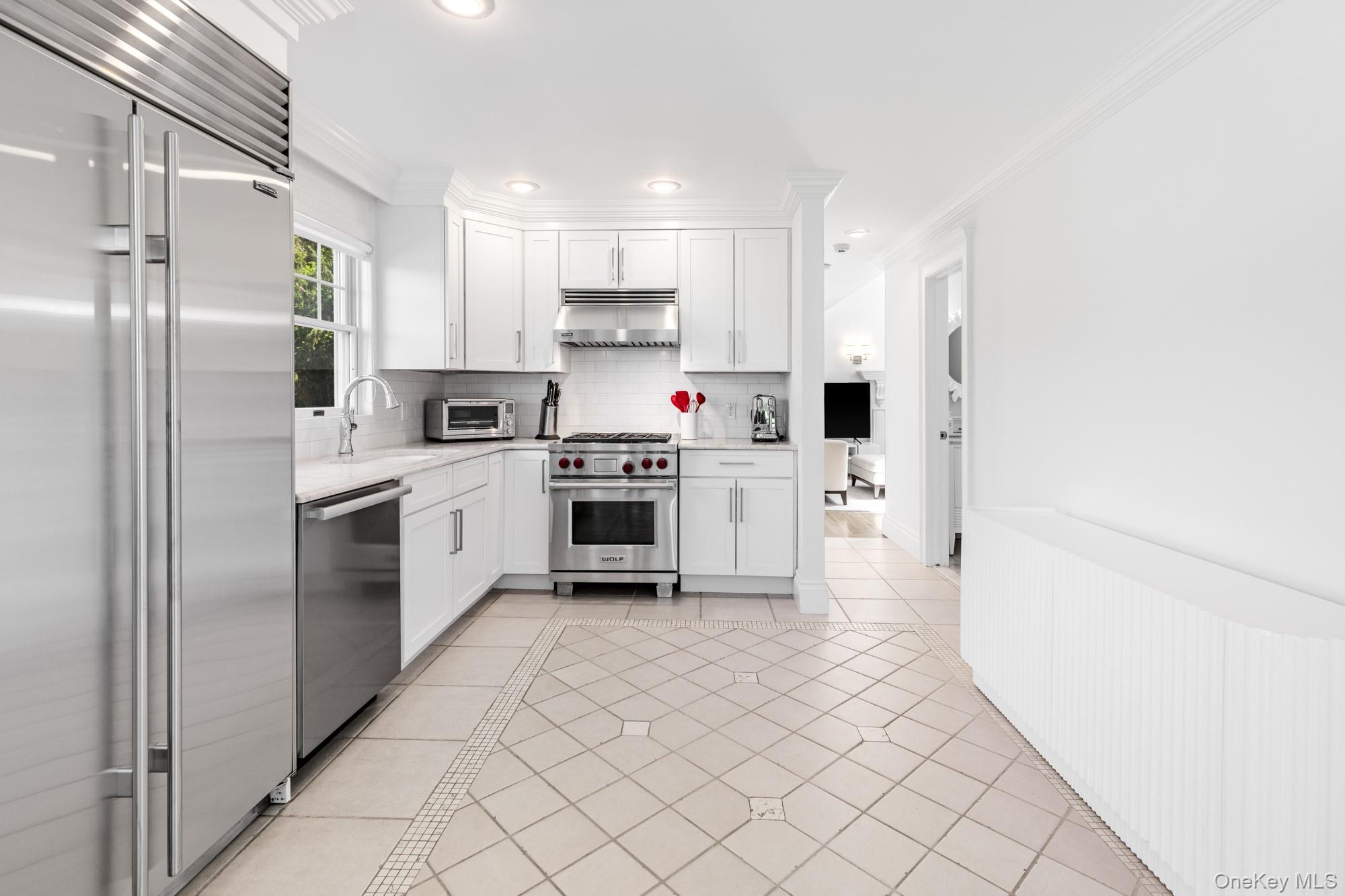 5 Lower 7 Ponds Road Water Mill, NY 11976 - Photo 12 of 35 Kitchen featuring premium appliances, under cabinet range hood, light countertops, light tile patterned floors, and a sink