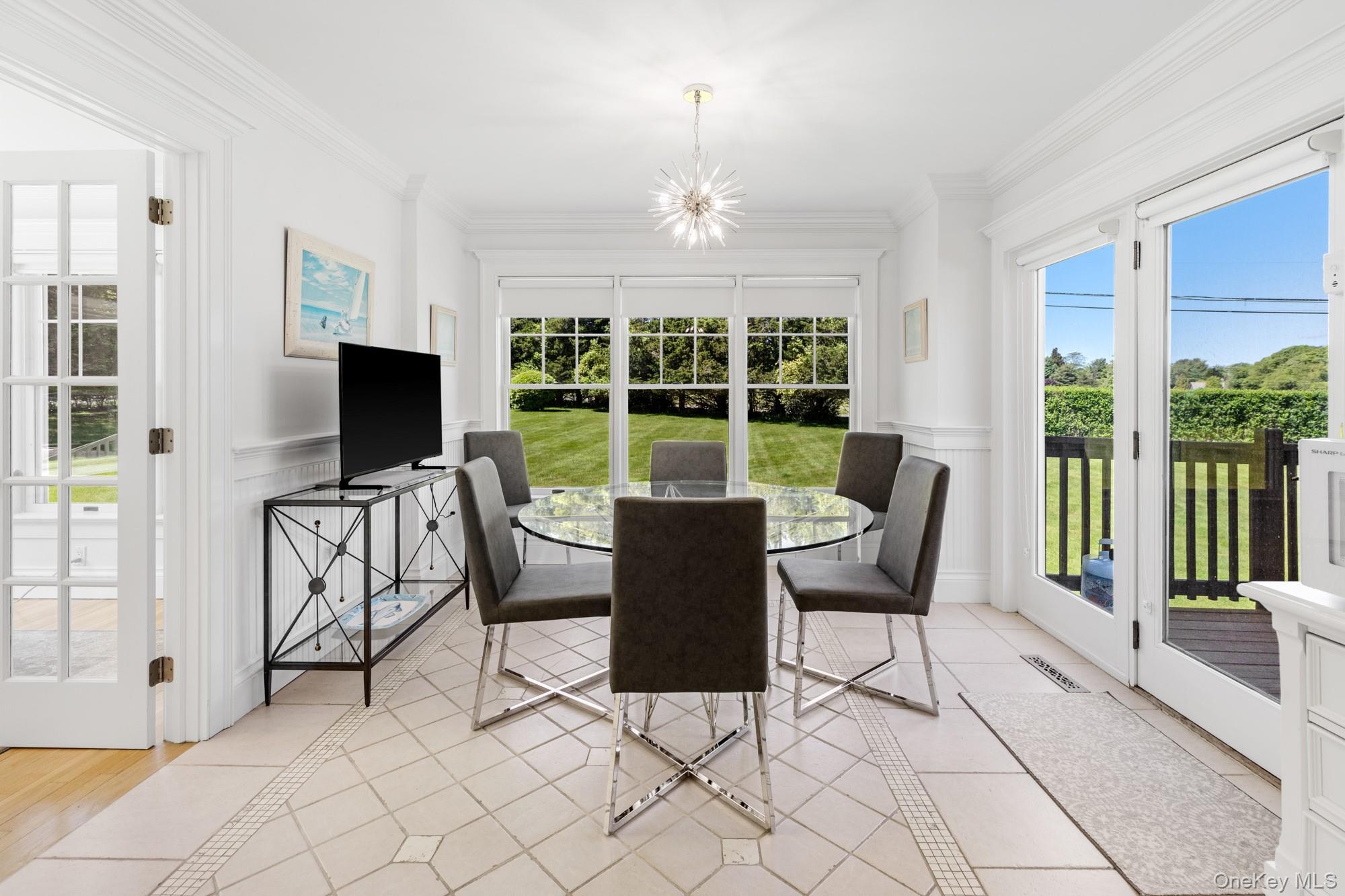 5 Lower 7 Ponds Road Water Mill, NY 11976 - Photo 13 of 35 Dining room with a chandelier, wainscoting, ornamental molding, and light tile patterned flooring