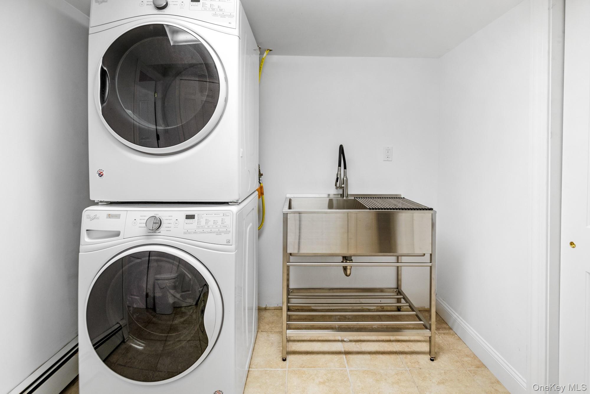 5 Lower 7 Ponds Road Water Mill, NY 11976 - Photo 28 of 35 Laundry room featuring a baseboard heating unit, estacked washer and dryer, and tile patterned floors