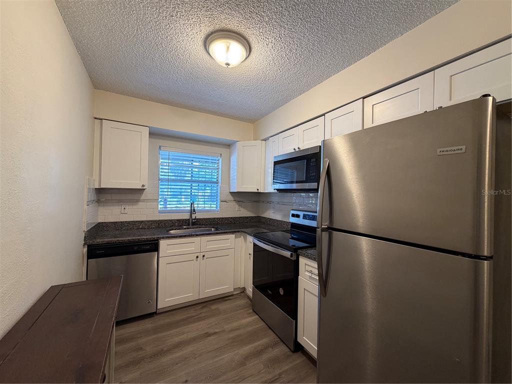 1740 West Walnut Street Tampa, FL 33607 - Photo 8 of 28 a kitchen with stainless steel appliances a refrigerator a sink and white cabinets