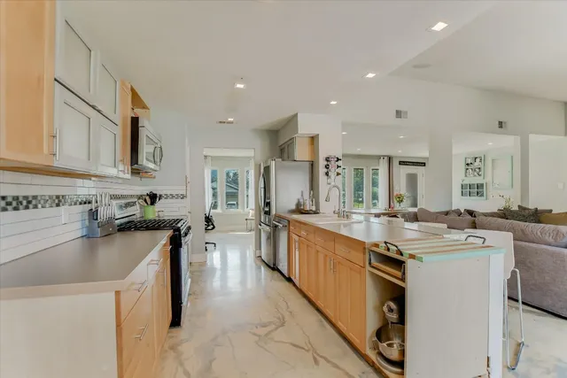 a kitchen with stainless steel appliances a stove a sink a refrigerator and a refrigerator