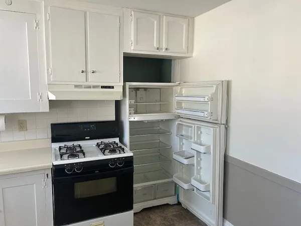 a kitchen with white cabinets and appliances