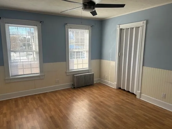 a view of an empty room with a window and wooden floor