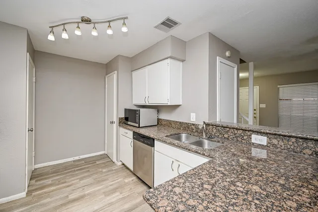 a kitchen with granite countertop a stove a sink and a refrigerator
