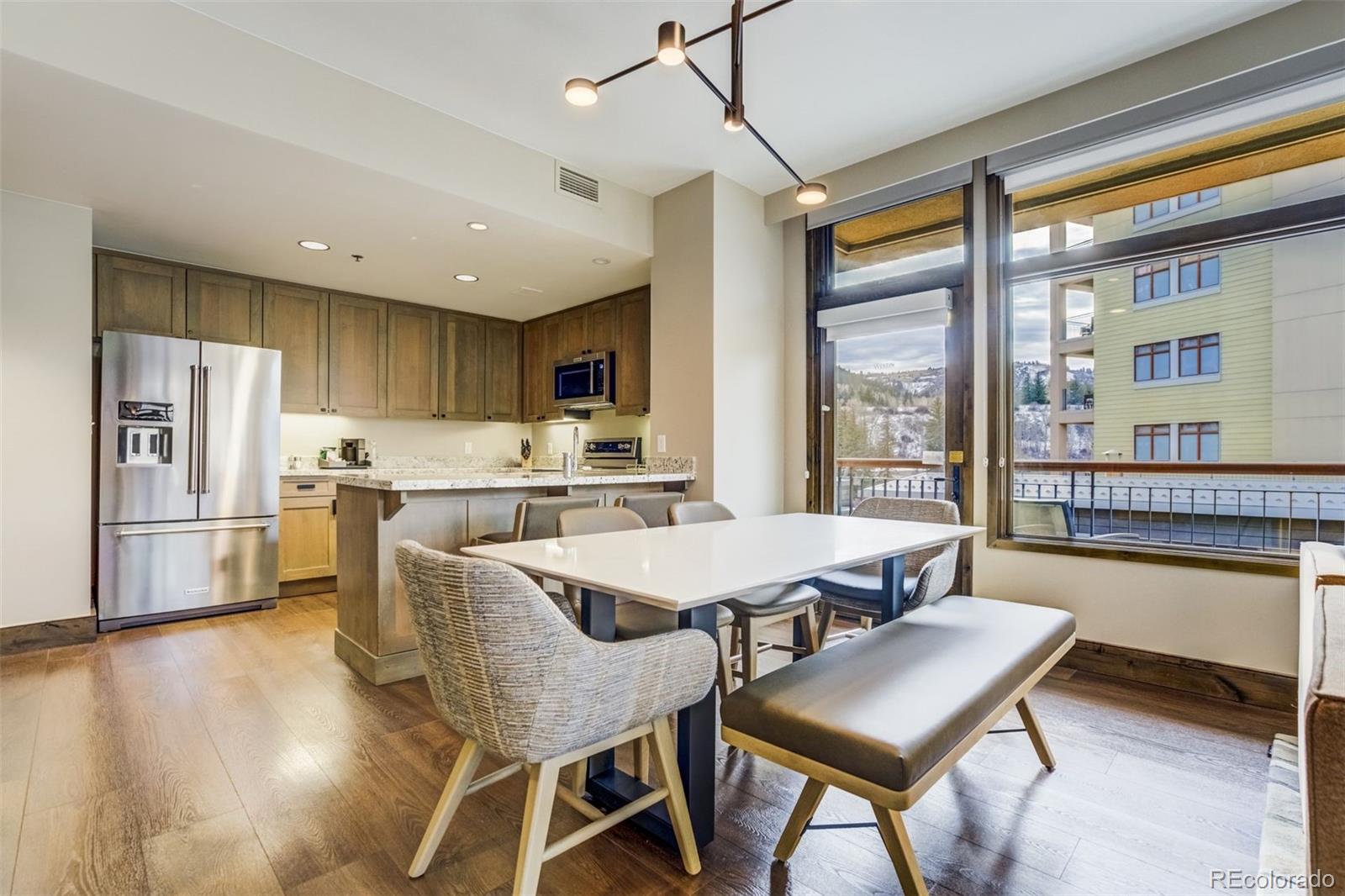 126 Riverfront Lane, Unit 200 Avon, CO 81620 - Photo 17 of 49 a kitchen with a table chairs refrigerator and microwave