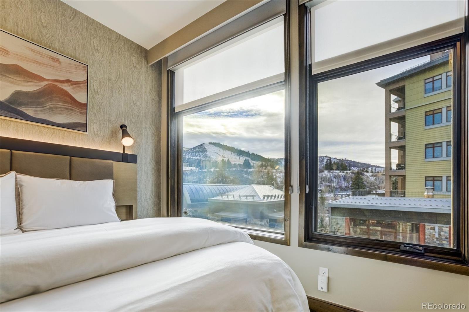 126 Riverfront Lane, Unit 200 Avon, CO 81620 - Photo 29 of 49 a bedroom with a large window and a bed