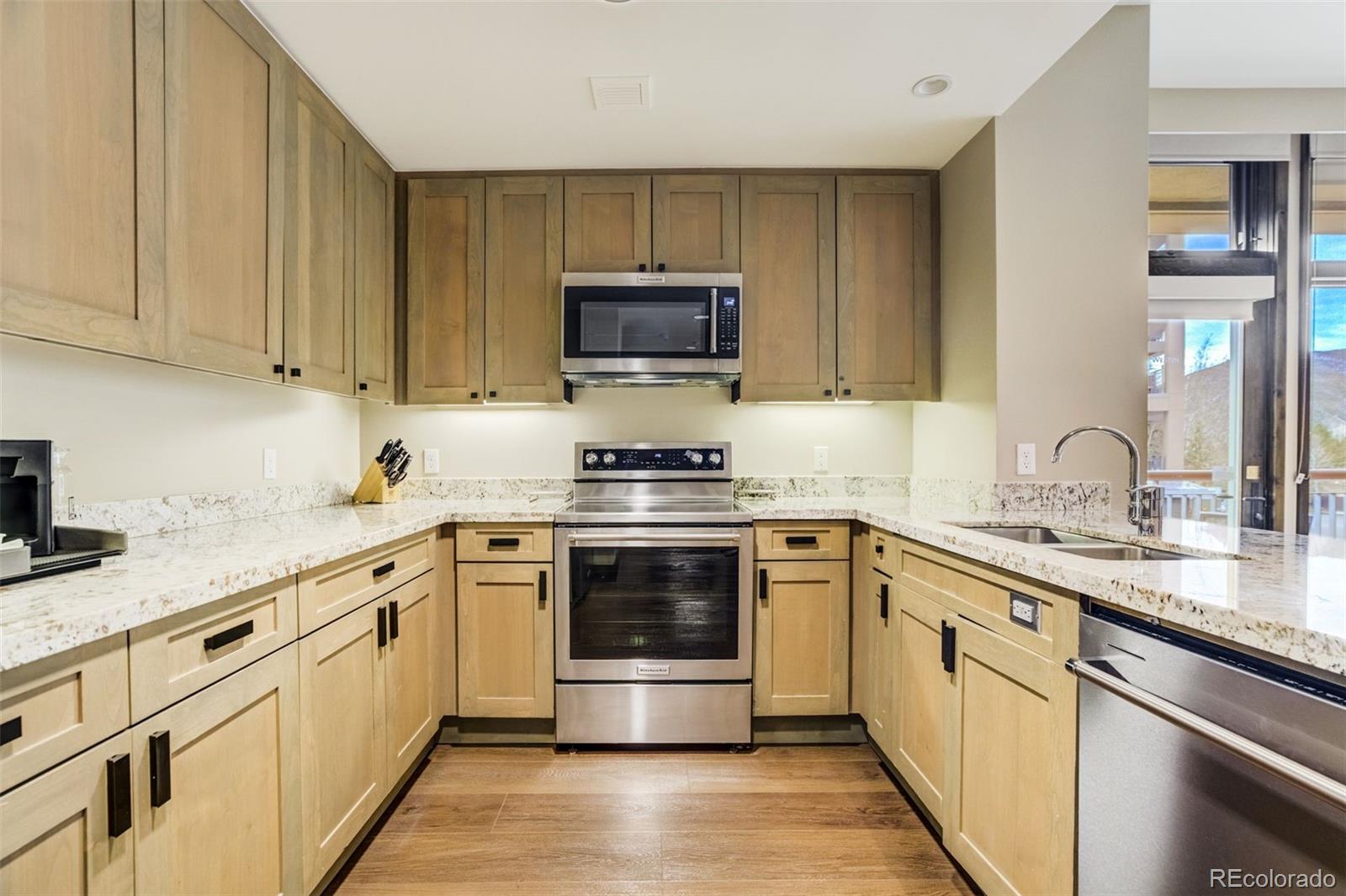 126 Riverfront Lane, Unit 200 Avon, CO 81620 - Photo 10 of 49 a kitchen with granite countertop a stove sink and cabinets