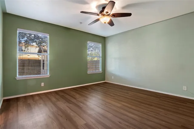 a view of an empty room with window and wooden floor