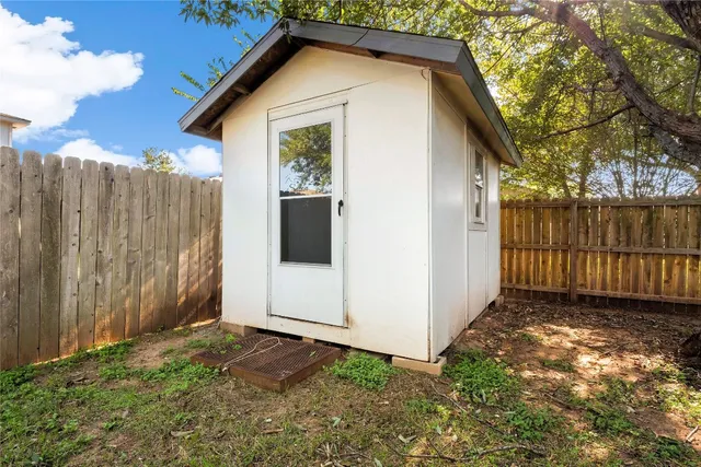 a view of a small house with wooden fence