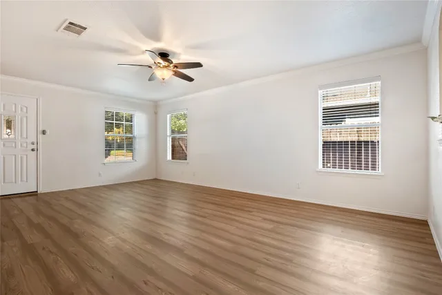 a view of empty room with wooden floor and fan