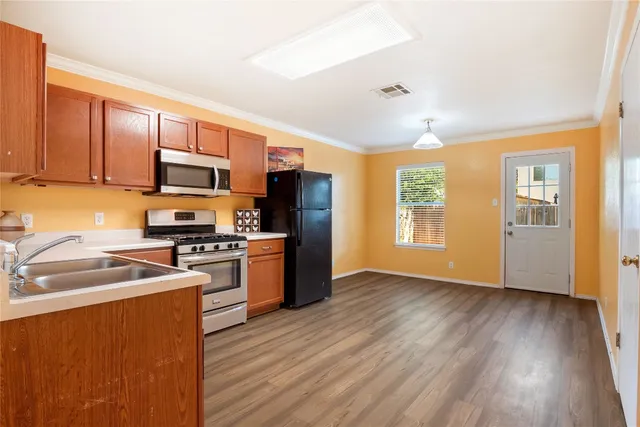 a kitchen with stainless steel appliances granite countertop a stove a sink dishwasher a refrigerator and a microwave oven with wooden floor