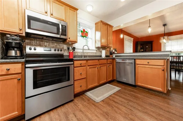 a kitchen with stainless steel appliances a stove a sink and a microwave