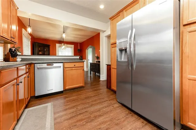 a kitchen with stainless steel appliances granite countertop a refrigerator a sink and white cabinets