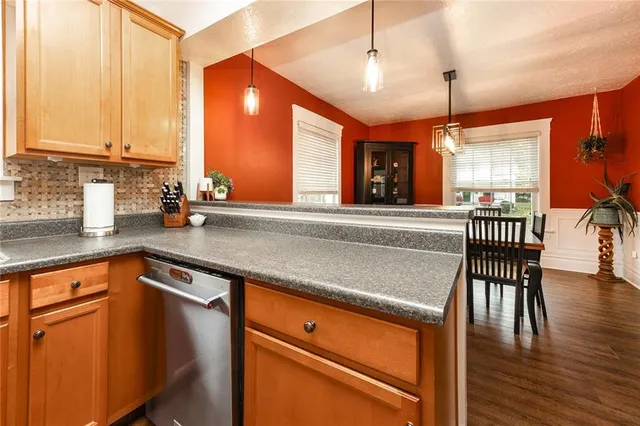 a kitchen with stainless steel appliances granite countertop wooden floor window dining table and chairs