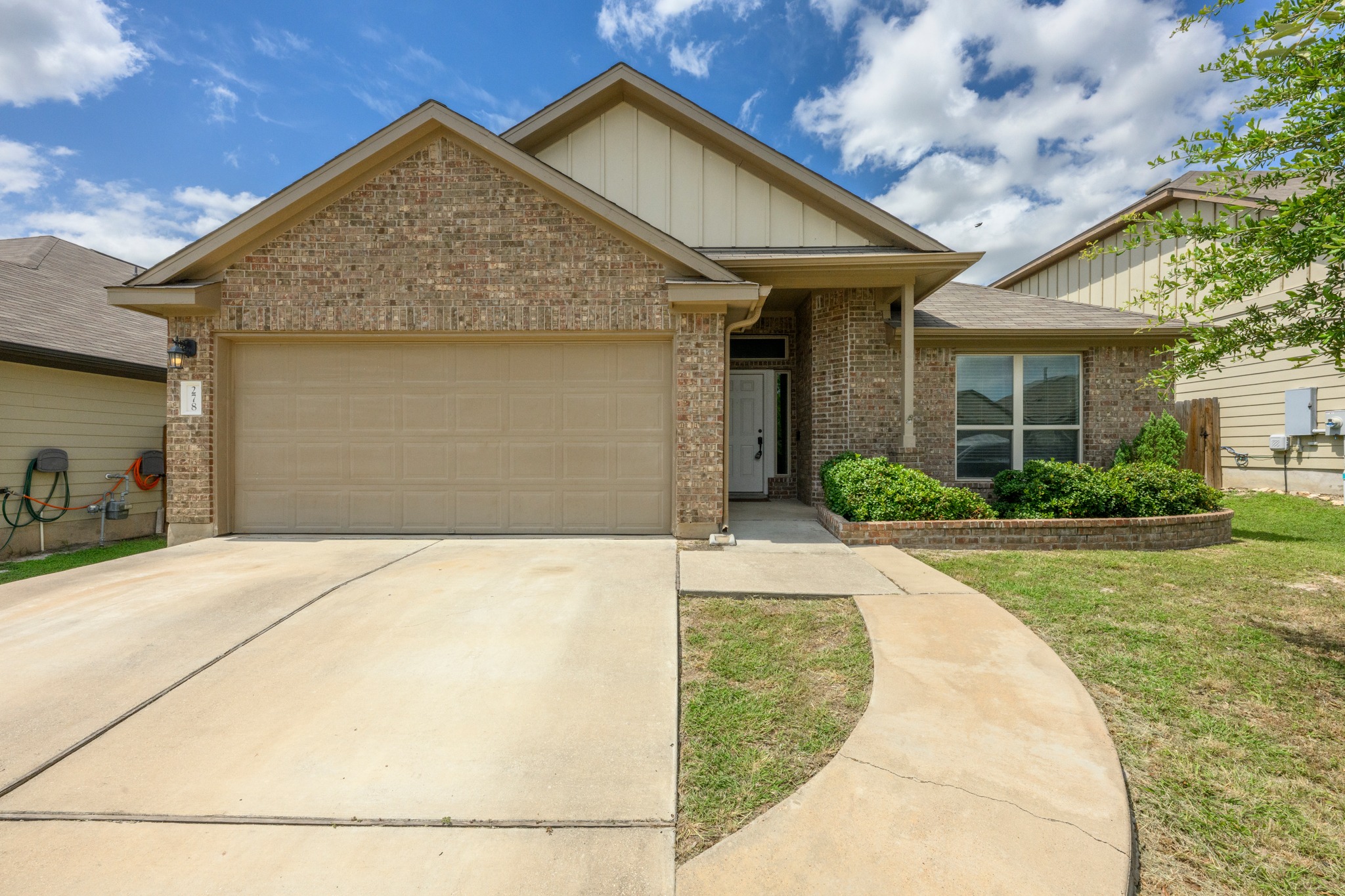 278 Noddy Road Buda, TX 78610 - Photo 17 of 17 A classic brick exterior with well-maintained landscaping and a welcoming curved pathway.