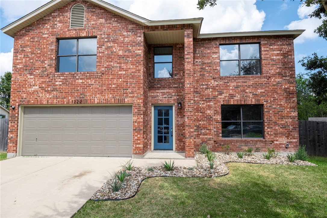 front view of a brick house with a yard
