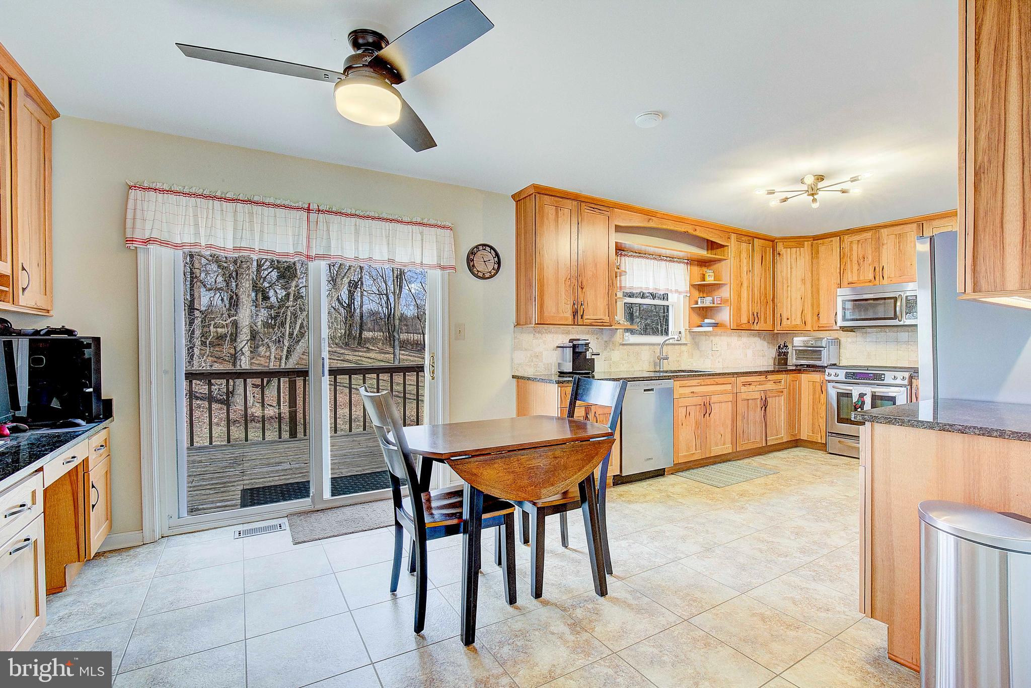 9150 Mackall Road St. Leonard, MD 20685 - Photo 12 of 48 a kitchen with stainless steel appliances granite countertop a stove top oven a sink dishwasher and a refrigerator with wooden cabinets