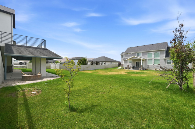 1002 West Temple Rim Lane Payson, UT 84651 - Photo 56 of 68 Expansive grassy yard featuring a covered patio, built-in fire pit, and a second-story balcony with metal railing