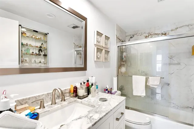 a bathroom with a granite countertop sink mirror and a toilet