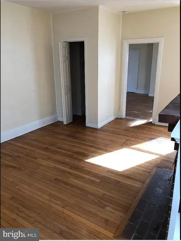 a view of an empty room with wooden floor and closet