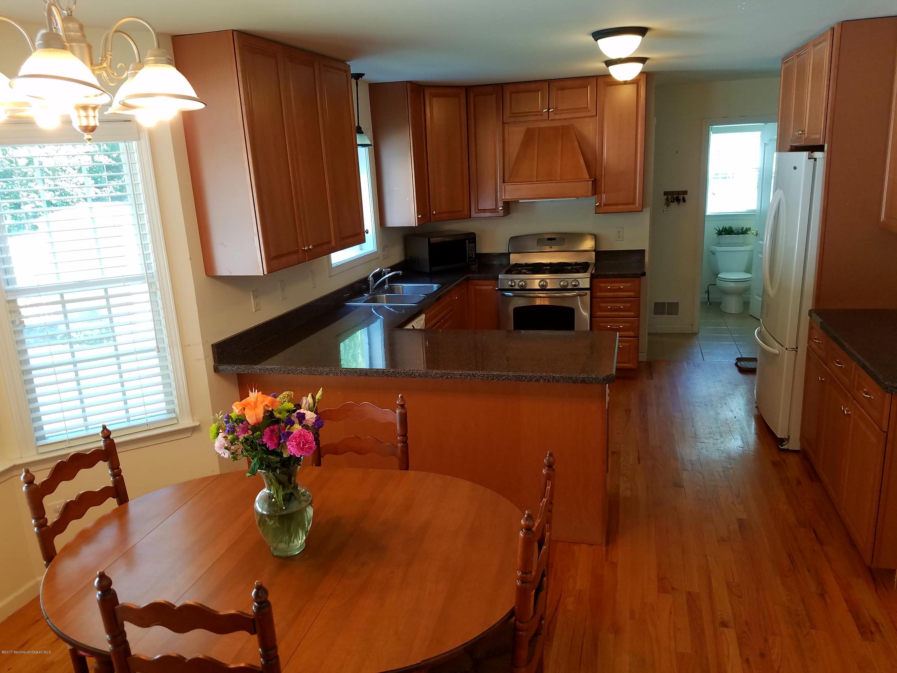126 Robin Road Neptune Township, NJ 07753 - Photo 2 of 24 a kitchen with stainless steel appliances granite countertop a stove a sink dishwasher and a dining table with wooden floor