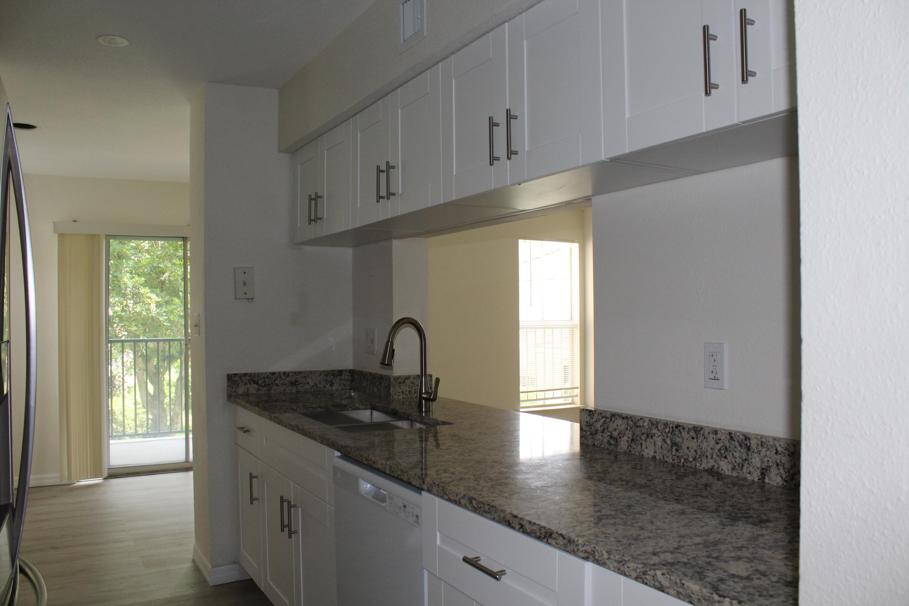 899 Riverside Drive, Unit 620 Coral Springs, FL 33071 - Photo 20 of 46 a kitchen with granite countertop a sink window and cabinets