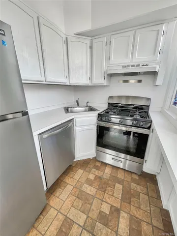a kitchen with white cabinets appliances and a sink