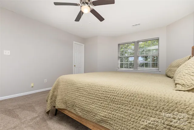 a bed sitting in a spacious bedroom next to a window