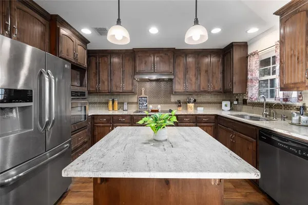 a kitchen with kitchen island granite countertop a sink a counter top space appliances and cabinets