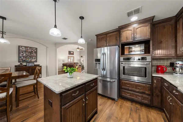 a kitchen with granite countertop a refrigerator and wooden floor