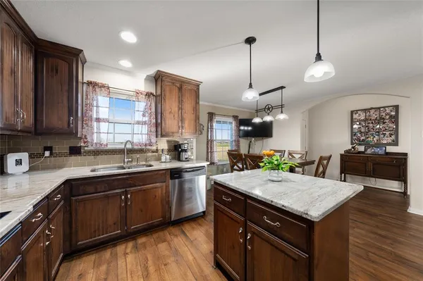 a kitchen with a stove center island a sink cabinets and wooden floor