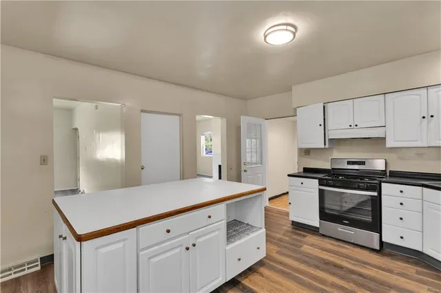 a kitchen with cabinets stainless steel appliances a sink and wooden floor