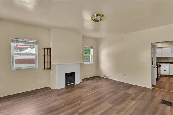 a view of empty room with wooden floor and fireplace