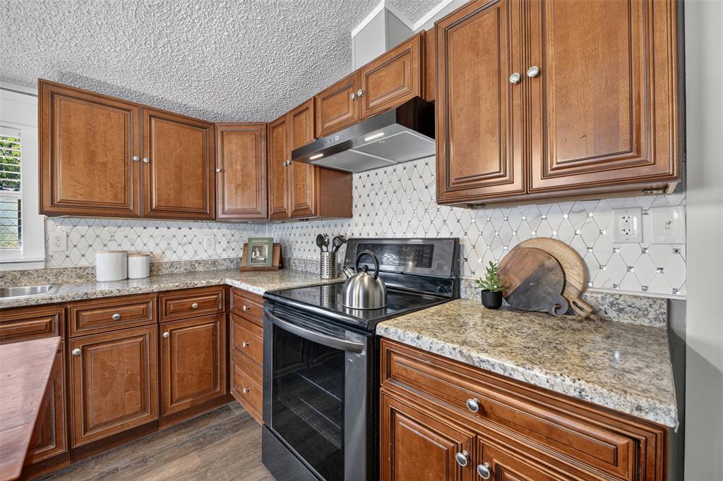 449 Big Salty Lane Springtown, TX 76082 - Photo 9 of 25 Kitchen featuring abundant wood cabinetry, granite-style countertops, mosaic tile backsplash, stainless steel sink, and wood-finish flooring