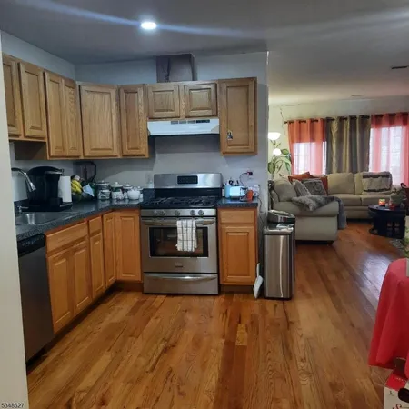 a kitchen with stainless steel appliances granite countertop a stove top oven a sink dishwasher and cabinets with wooden floor