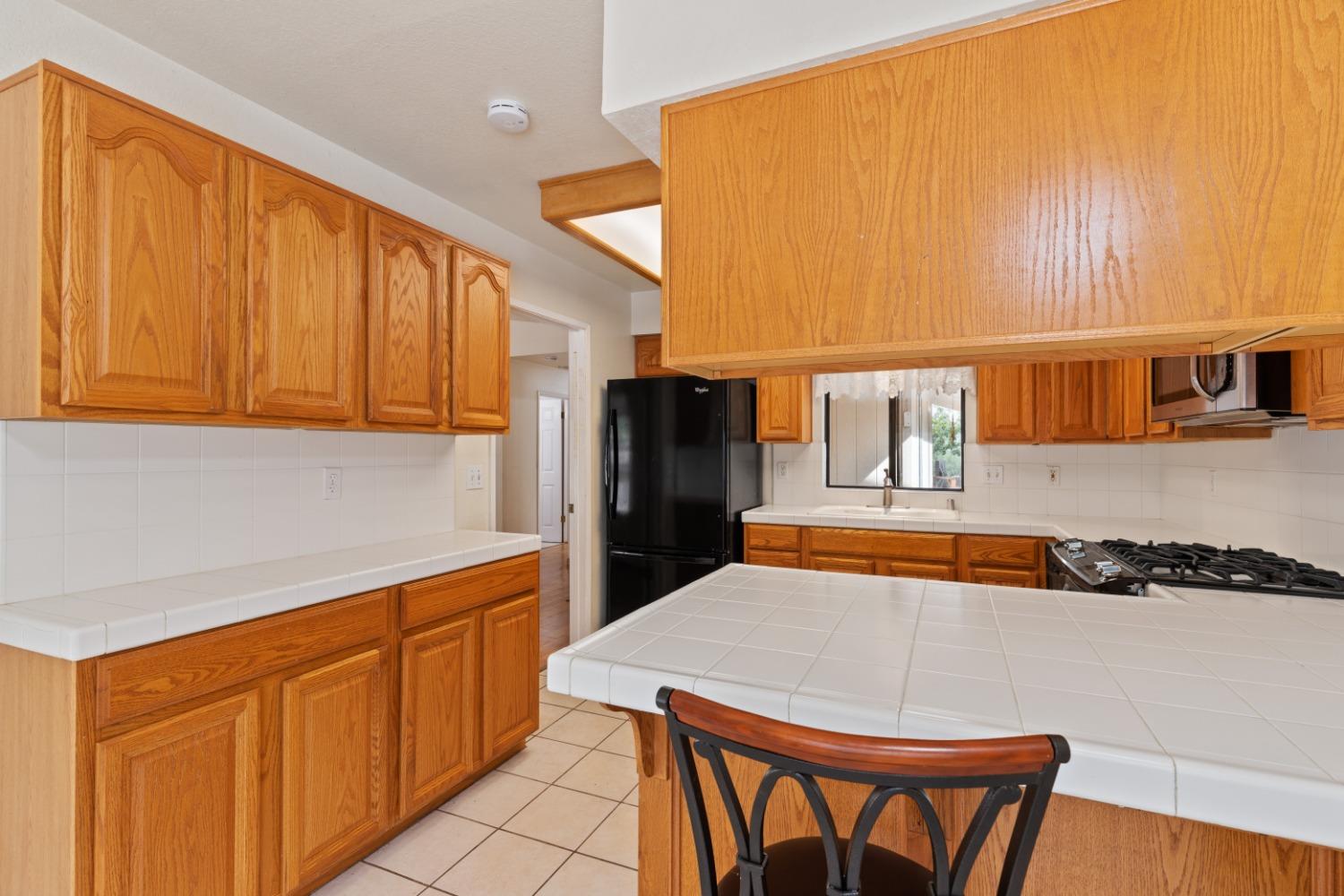 40809 Jean Road West Oakhurst, CA 93644 - Photo 15 of 39 a kitchen with stainless steel appliances kitchen island granite countertop a refrigerator and wooden cabinets