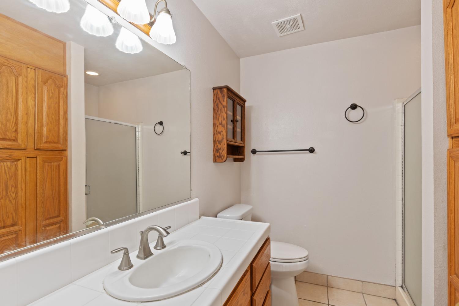 40809 Jean Road West Oakhurst, CA 93644 - Photo 25 of 39 a bathroom with a sink a toilet a mirror and shower curtain