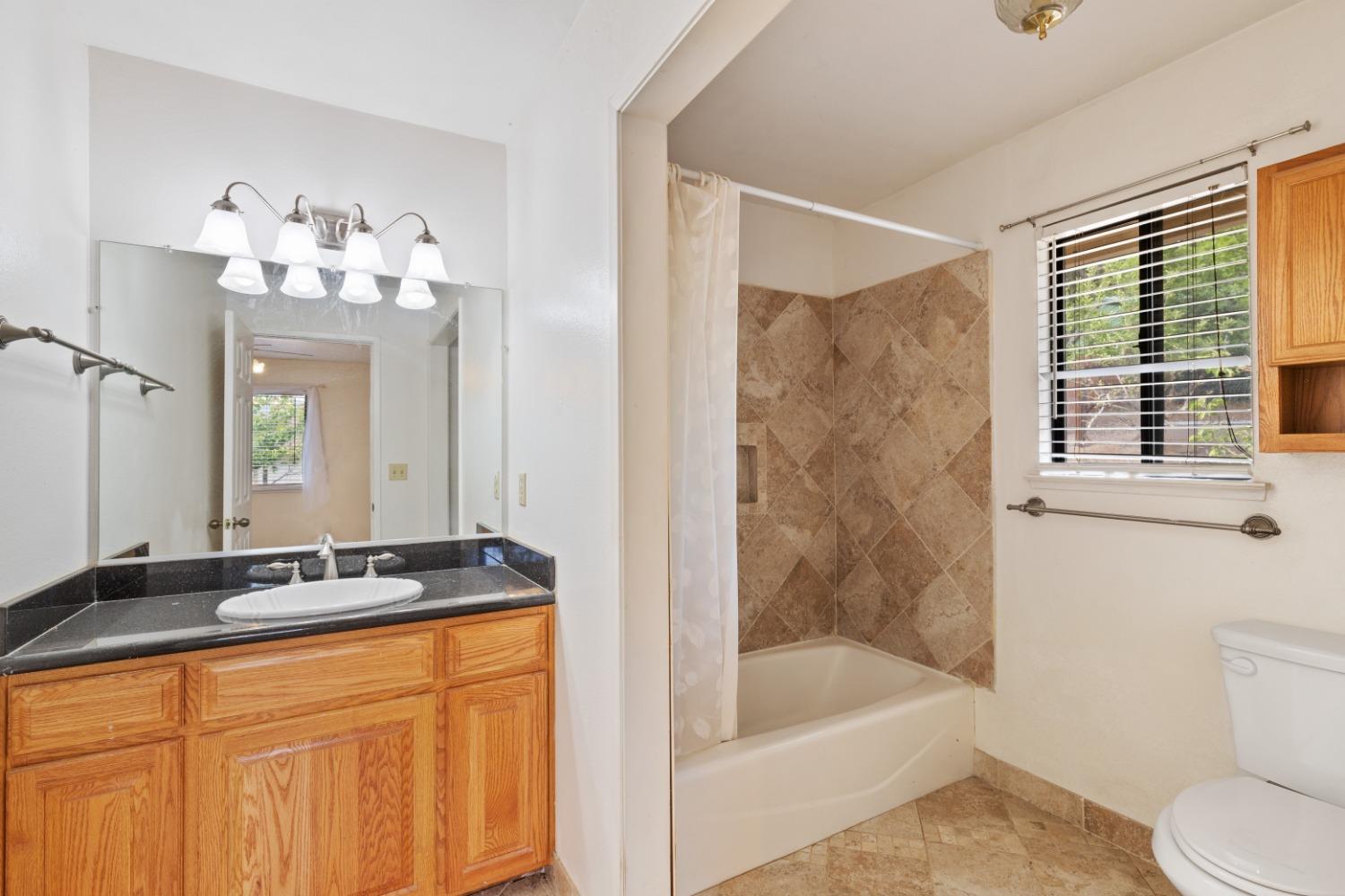 40809 Jean Road West Oakhurst, CA 93644 - Photo 29 of 39 a bathroom with a granite countertop sink a toilet a mirror and bathtub